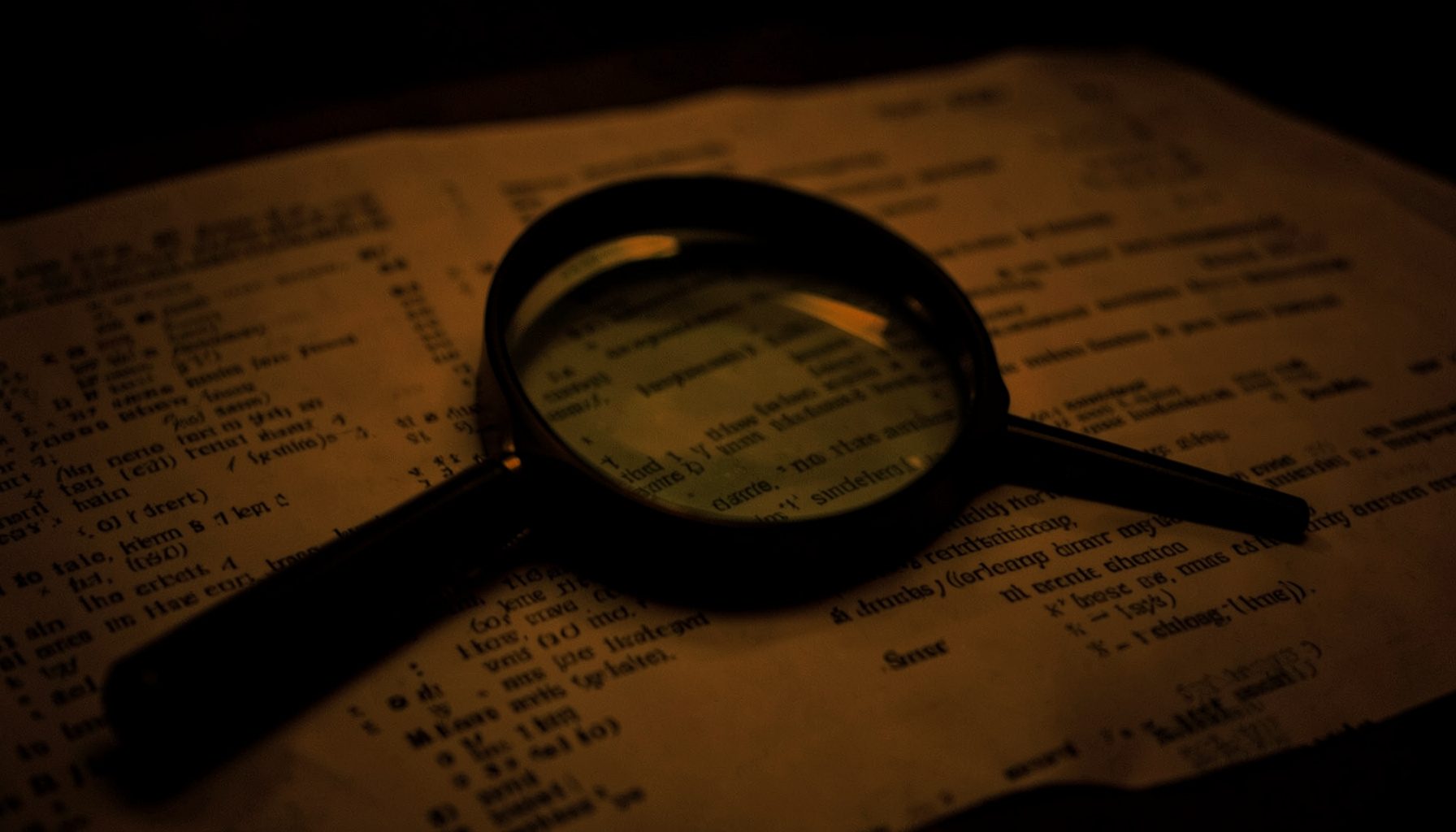 A dim photograph of a magnifying glass resting on printouts of search results in muted amber tones.