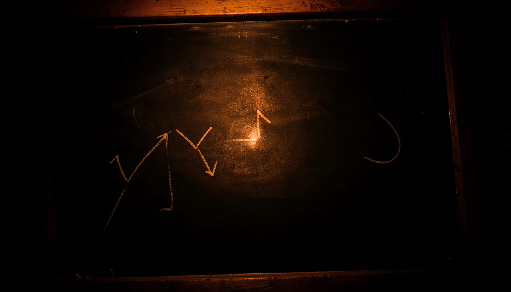 A moody overhead shot of a chalkboard with hand-drawn growth arrows under warm low lighting.